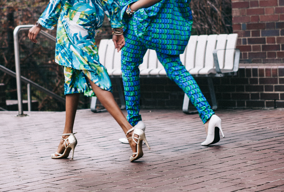 Two women in high heels strolling down a brick street